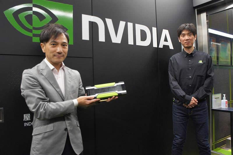 NVIDIA社名ロゴの前に立つ佐々木様と当社森